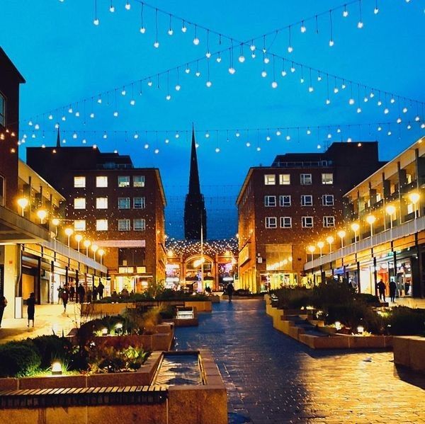 Coventry city centre at night looking towards the cathedral spire with lots of fairy lights